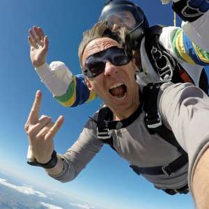 Selfie of excited skydiver screaming with joy during tandem skydiving freefall near Nashville